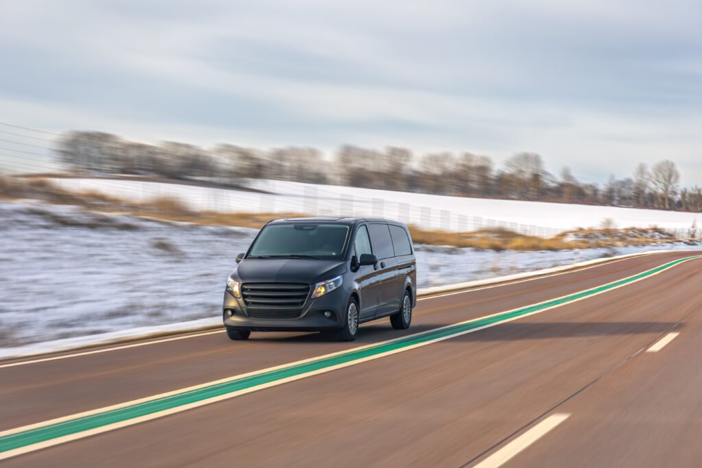 minivan driving on winter road across snowy countryside landscape. car travel transport.